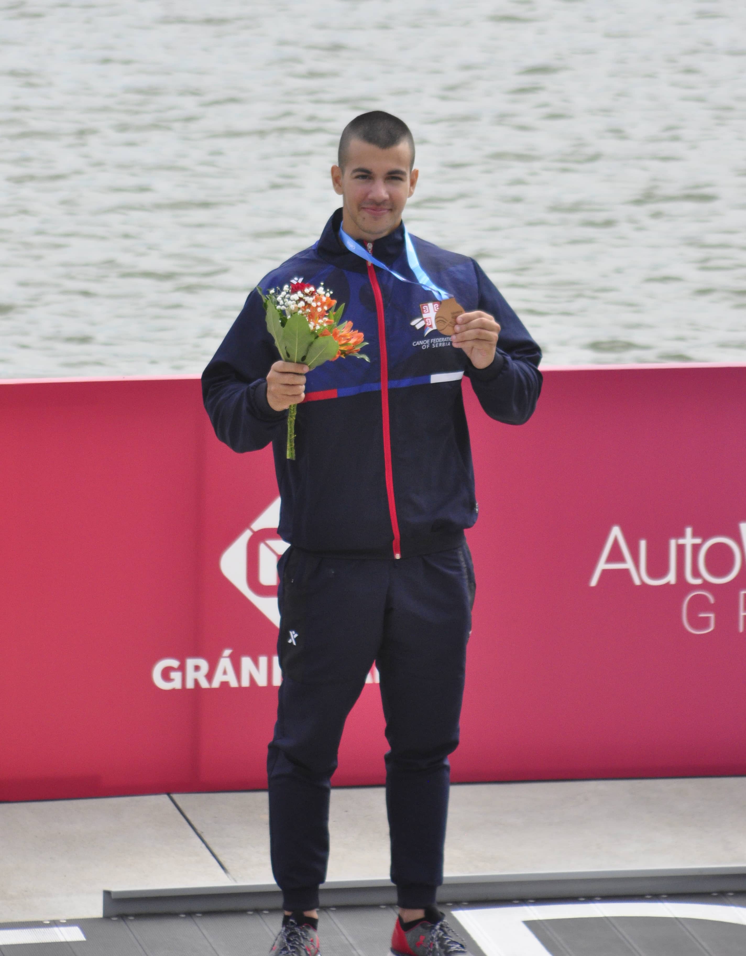 Bojan Zdelar holding his medal and flowers after a championship race